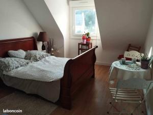 a bedroom with a bed and a table and a window at Maison plein sud 300m petite mer de Gâvres in Riantec