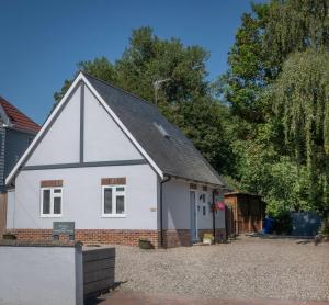 a white house with a black roof at Hedgehog Cottage in Bury Saint Edmunds