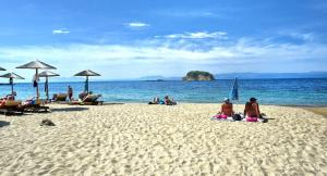 a group of people sitting on a beach at Hotel Korali in Troulos