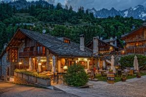 a house in the mountains with tables and chairs at Hotel Pilier D'Angle & Wellness in Courmayeur
