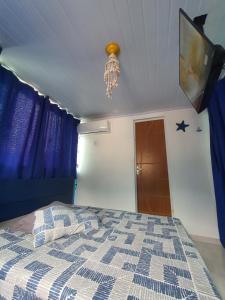 1 dormitorio con 1 cama con cortinas azules y lámpara de araña en Suite Bela vista Muriqui Cantinho Feliz, en Mangaratiba