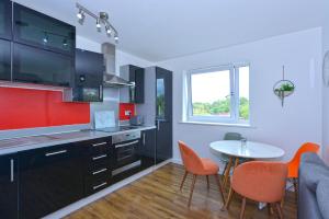a kitchen with a table and orange chairs and a table and a room at Broad Gauge Apartments in Wolverhampton