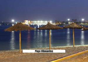 a group of straw umbrellas on a beach at night at Apartalux San Pedro Sol in San Pedro del Pinatar
