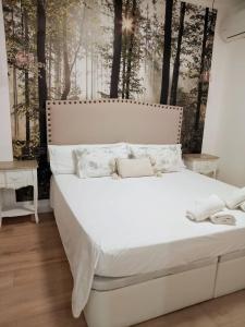 a white bed in a bedroom with trees on the wall at Oasis Suites Fernando IV in Seville