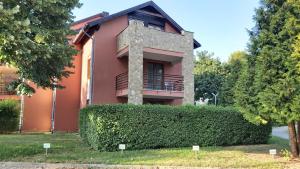 una casa rosa con una siepe davanti di Andante apartman a Bük