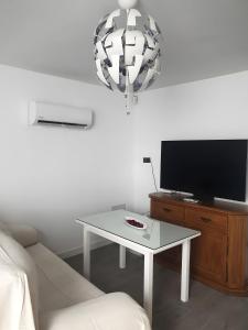 Una sala de estar con una mesa y un televisor. en Apartamentos Serranía, en Ronda