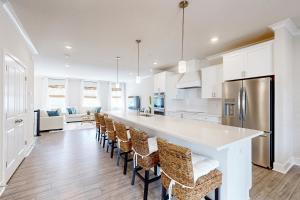 una cucina con armadi bianchi e un bar con sedie di Sea Oaks Village - Seascape 5 a Berlin