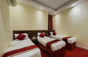 a hotel room with two beds with red pillows at فندق صفوة المشاعر in Al Khansāk
