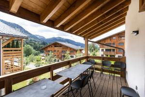 a balcony with a table and chairs and mountains at TERRESENS - L'Eclat des Veriaz - Megève - Praz-sur-Arly - New in Megève