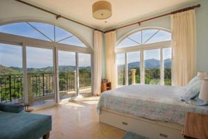 a bedroom with large windows and a bed with a view at Acqua 801 in Jacó