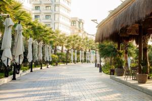 a sidewalk with umbrellas and palm trees on a street at Red apartment in Golem