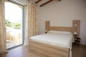 a bedroom with a bed and a large window at Motel le Vieux Moulin in LʼÎle-Rousse