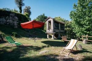 einen roten Regenschirm und zwei Stühle im Hof in der Unterkunft Quinta da Azenha by House and People in Valdosende
