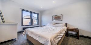 a white bedroom with a bed and a window at Elegant 2 Bedroom Apartment in Bromley