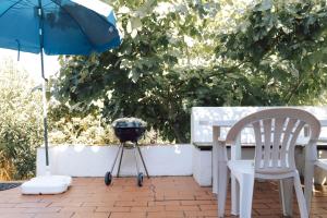 a grill and a table with a chair and an umbrella at Jardim de Vénus in Vila de Frades
