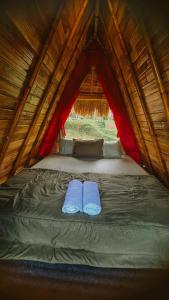 a bed in a tent with two blue slippers at Swaha Retreat & Eco Park Ubud in Tampaksiring