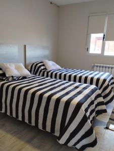 two beds with black and white striped sheets in a room at Descanso en el Sur in Playa Unión