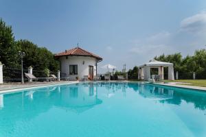 a large blue swimming pool with a house in the background at Villa Massa in San Damiano dʼAsti