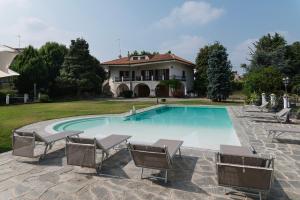a swimming pool with chairs and a house at Villa Massa in San Damiano dʼAsti