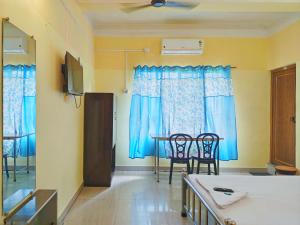a room with blue curtains and a table and chairs at Ushashee Amidst Nature in Siliguri