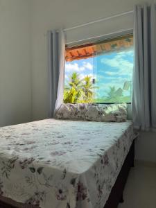 a bed with a window with a view of the ocean at Casa da praia Ilha Grande in Camamu