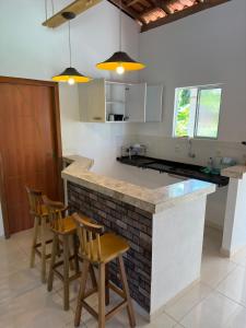 a kitchen with a counter with chairs around it at Casa da praia Ilha Grande in Camamu