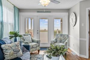 a living room with two chairs and a clock at Waters Edge 433-C OBW in Holden Beach +38 photos