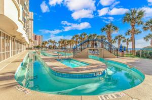a swimming pool at a resort with palm trees at Coastal King Suite-Ocean Views-Boardwalk 640 in Myrtle Beach