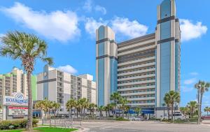 a large building with palm trees in a parking lot at Coastal King Suite-Ocean Views-Boardwalk 640 in Myrtle Beach