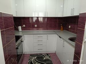 a kitchen with white cabinets and a sink at Apartman Orhideja in Višegrad