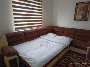 a brown couch in a room with a window at Apartman Orhideja in Višegrad +5 photos