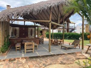 a patio with tables and chairs and a straw umbrella at Chaleville Maramar in Luis Correia