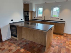 an empty kitchen with a large island in the middle at The Farm Cottage in Waregem