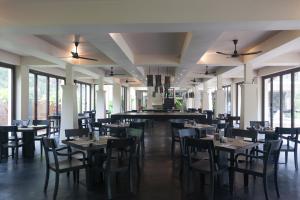 a dining room with tables and chairs and windows at Grand Southsea Khaolak Beach Resort in Khao Lak