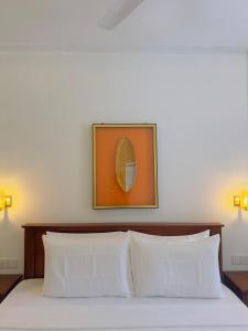 a bed with two pillows and a picture on the wall at Alloy Heights Hotel & Apartments in Kandy