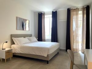 a bedroom with a white bed and blue curtains at Casa FILA1923 in Biella