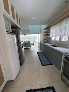 a kitchen with a white refrigerator and a table at Alto padrão piscina Praia Mococa in Caraguatatuba +36 photos
