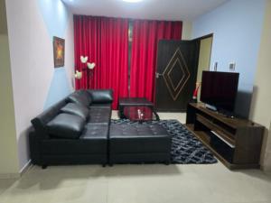 a living room with a black leather couch and a television at Quirpinchaca Premier in Sucre