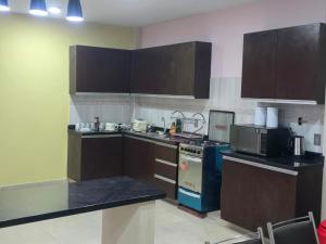 a kitchen with brown cabinets and a blue stove at Quirpinchaca Premier in Sucre +12 photos