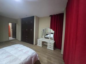 a bedroom with a bed and a mirror and red curtains at Quirpinchaca Premier in Sucre