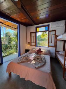 Un dormitorio con dos camas y una gran ventana. en Vila Pequeá Ilhabela, en Ilhabela
