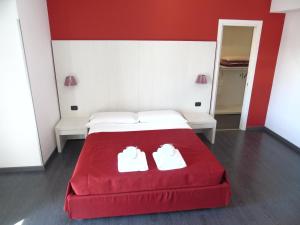 a red and white bed with two white shoes on it at Areté Luxury Room in Reggio di Calabria +38 photos
