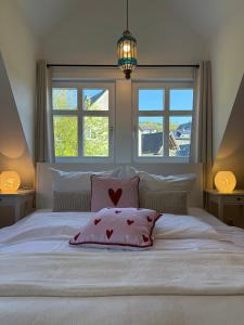a white bed with a red pillow and two windows at Ferienwohnung Vierländereck nahe Winterberg in Elpe
