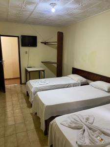 a room with three beds and a flat screen tv at Hotel Vale Das Serras in Jacobina +5 photos