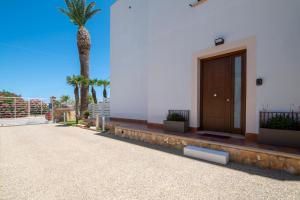 a palm tree next to a building with a door at Villa Giunella in San Vito lo Capo
