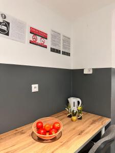 a wooden table with a bowl of tomatoes on it at Gołębia Group Room in Poznań