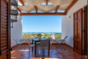 サン・ヴィート・ロ・カーポにあるVilla Giunellaのテーブルと椅子と大きな窓のあるダイニングルーム