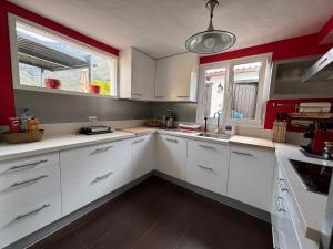 a white kitchen with red walls and white cabinets at Los Veroles in Agaete +50 photos
