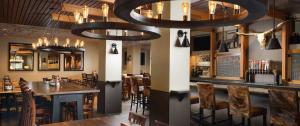 沃思堡Embassy Suites by Hilton Fort Worth Downtown的带酒吧的餐厅，酒吧里有椅子和桌子