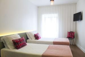 a hotel room with two beds and a television at Casa da Tasquinha in Ponta Delgada